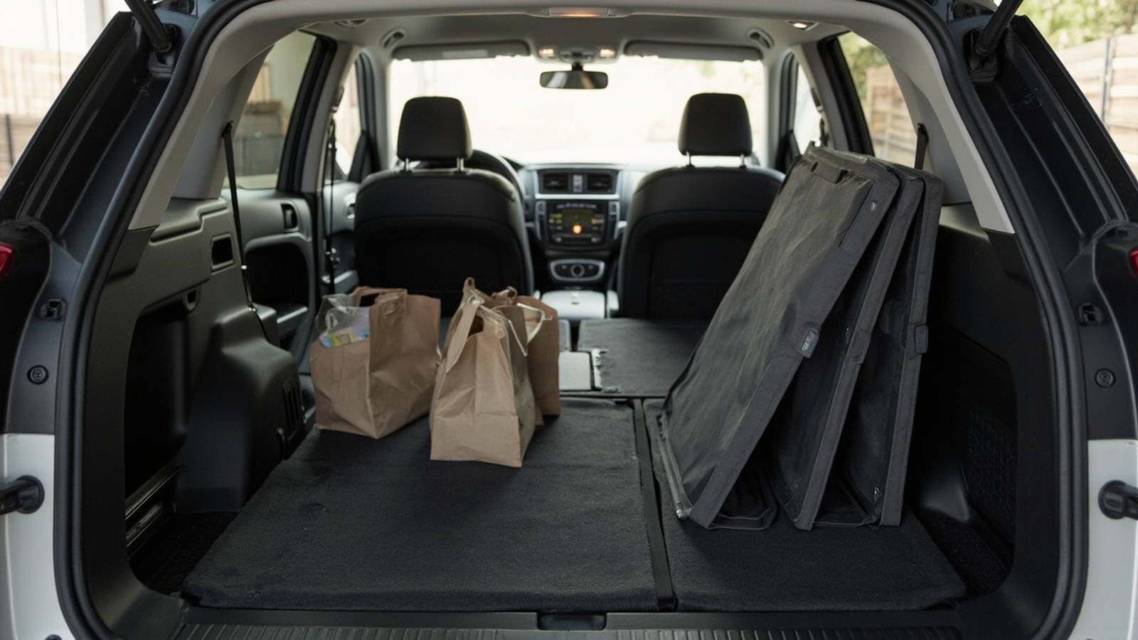 Folded wagon standing upright in an open SUV cargo area with grocery bags beside it
